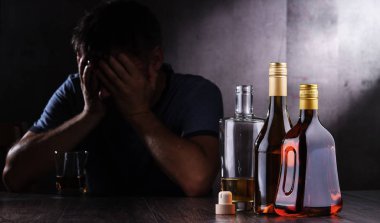 Alkol dolu şişeler ve sarhoş bir adam figürü.