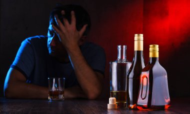 Alkol dolu şişeler ve sarhoş bir adam figürü.