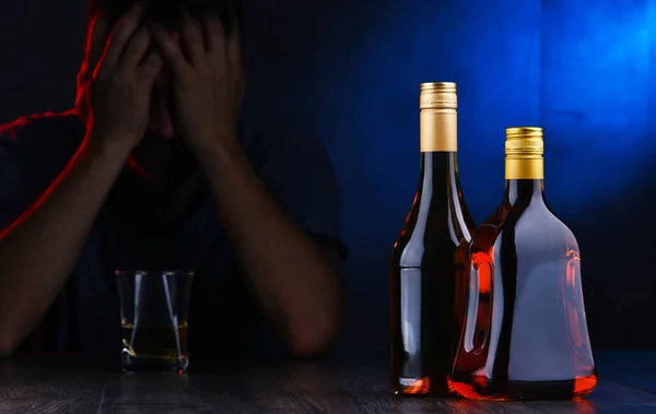 Üvegek alkoholtartalmú italokkal és egy részeg ember alakja — Stock Fotó