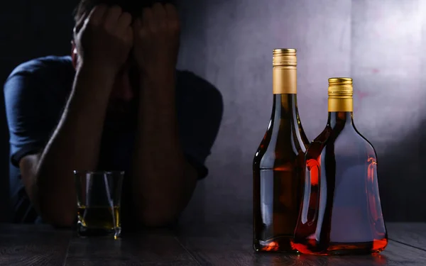 Üvegek alkoholtartalmú italokkal és egy részeg ember alakja — Stock Fotó