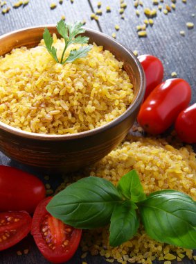 Ahşap masada pişmemiş bir kase bulgur.