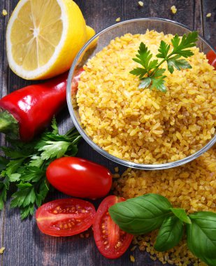 Ahşap masada pişmemiş bir kase bulgur.