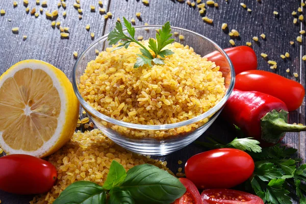 Bowl van ongekookte bulgur op houten tafel — Stockfoto