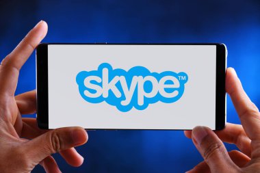 Skype logosunu görüntüleyen akıllı telefonu tutan eller