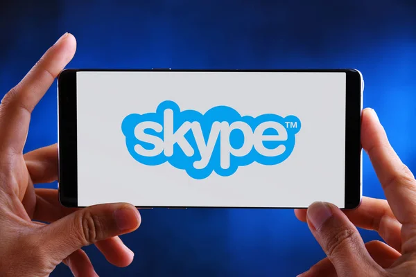 Hands holding smartphone displaying logo of Skype — Stock Photo, Image