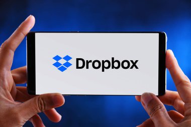 Hands holding smartphone displaying logo of Dropbox clipart
