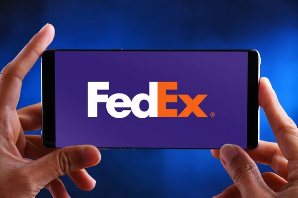 Mãos segurando smartphone exibindo logotipo da FedEx — Fotografia de Stock