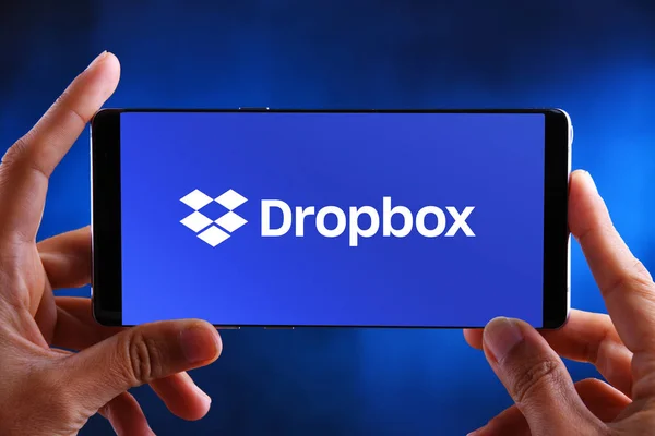 Dropbox のロゴを表示するスマートフォンを手に持つ — ストック写真