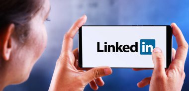 Linkedin logosunu gösteren akıllı telefon tutan kadın