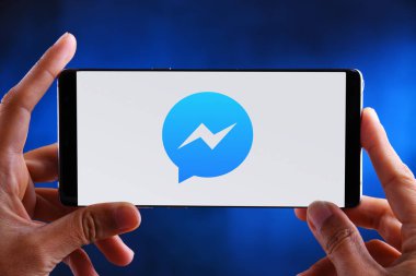 Facebook Messenger logosunu gösteren akıllı telefonu tutan eller