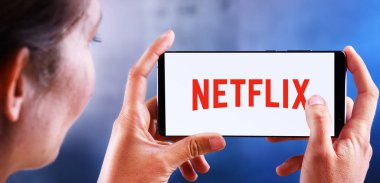Netflix logosunu gösteren akıllı telefon tutan kadın