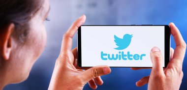 Twitter logosunu gösteren akıllı telefon tutan kadın