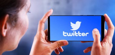 Twitter logosunu gösteren akıllı telefon tutan kadın