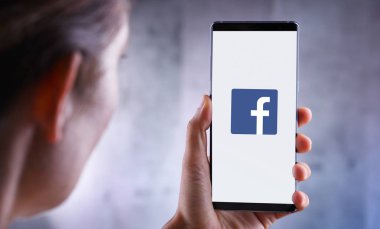 Facebook logosunu gösteren akıllı telefon tutan kadın
