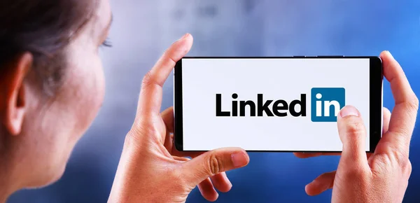 Woman holding smartphone displaying logo of LinkedIn — Stock Photo, Image