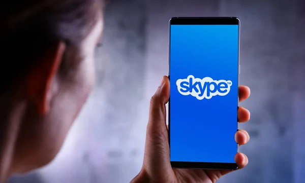 Wanita memegang smartphone menampilkan logo Skype — Stok Foto