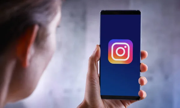 Perempuan yang memegang smartphone menampilkan logo Instagram — Stok Foto