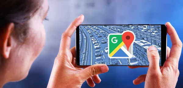 Perempuan yang memegang smartphone menampilkan logo Google Maps — Stok Foto