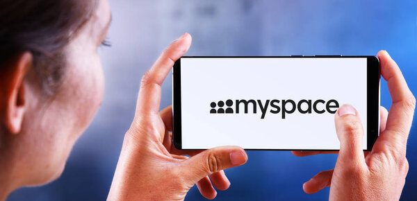 Woman holding smartphone displaying logo of Myspace