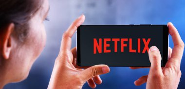 Netflix logosunu gösteren akıllı telefon tutan kadın