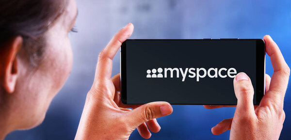 Woman holding smartphone displaying logo of Myspace