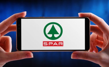 POZNAN, POL - 21 Mayıs 2020: SPAR 'ın akıllı telefon amblemini tutan eller, Hollanda' nın bağımsız sahibi olduğu ve işlettiği çok uluslu bir bayilik.