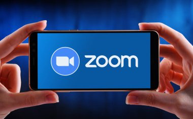 POZNAN, POL - 21 Mayıs 2020: Zoom, videotelephony ve çevrimiçi sohbet hizmetlerini gösteren akıllı telefonları bulut tabanlı bir paylaşımcı yazılım platformu üzerinden tutan eller