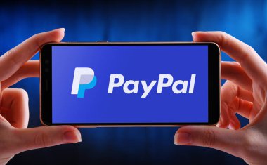 POZNAN, POL - MAY 21, 2020: Hand holding smartphone displaying logo of PayPal, an American company operating a worldwide online payments system that supports online money transfers