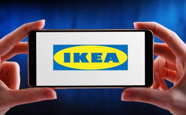 POZNAN, POL - 21 Mayıs 2020: Mobilya, mutfak gereçleri ve ev aksesuarları tasarlayan ve satan çok uluslu bir grup olan IKEA 'nın logosunu gösteren akıllı telefonları tutan eller