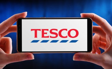 POZNAN, POL - MAY 21, 2020: Hands holding smartphone displaying logo of Tesco, a multinational groceries and general merchandise retailer with headquarters in Welwyn Garden City, Hertfordshire, Engl.
