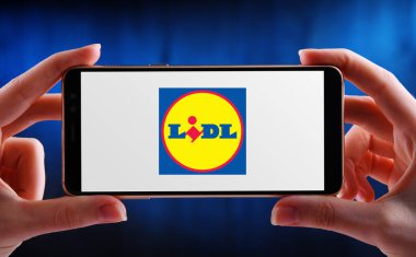 POZNAN, POL - 21 Mayıs 2020: Neckarsulm, Almanya merkezli küresel indirimli bir süpermarket zinciri olan Lidl 'in akıllı telefon logosunu gösteren eller