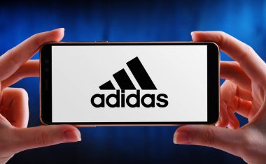 POZNAN, POL - 21 Mayıs 2020: Ayakkabı, giysi ve aksesuar tasarlayan ve üreten bir Alman şirketi olan Adidas 'ın akıllı telefon logosunu gösteren eller