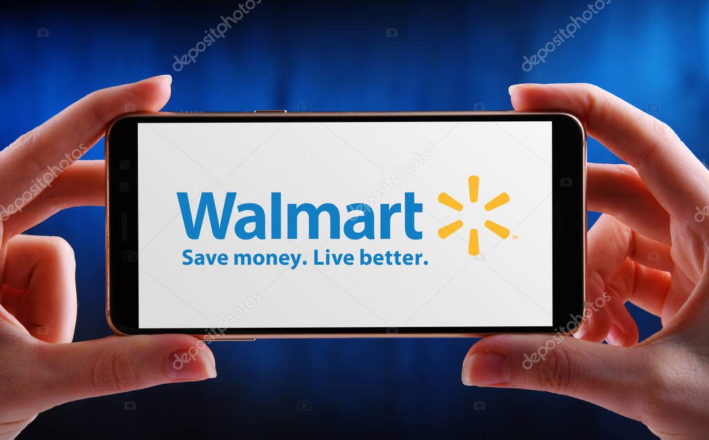 POZNAN, POL - MAY 21, 2020: Hands holding smartphone displaying logo of Walmart Inc., an American multinational retail corporation headquartered in Bentonville, Arkansas