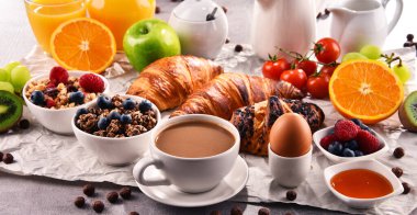 Kahvaltının yanında kahve, portakal suyu, kruvasan, yumurta, mısır gevreği ve meyve var. Dengeli diyet.