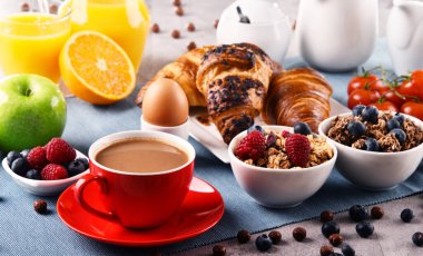Kahvaltının yanında kahve, portakal suyu, kruvasan, yumurta, mısır gevreği ve meyve var. Dengeli diyet.