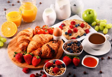 Kahvaltının yanında kahve, portakal suyu, kruvasan, yumurta, mısır gevreği ve meyve var. Dengeli diyet.