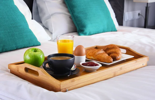 Breakfast on tray in bed in hotel room.