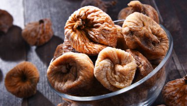 Ahşap masada bir kase kurutulmuş incir ile kompozisyon.