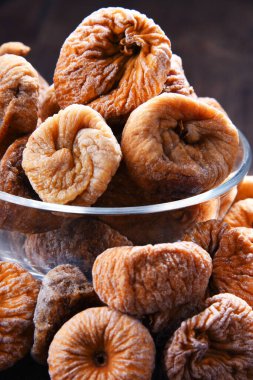 Ahşap masada bir kase kurutulmuş incir ile kompozisyon.