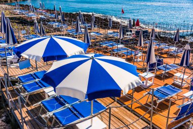 Sıcak yaz gününde kayalık bir sahilde şemsiyeler.