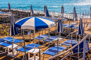 Sıcak yaz gününde kayalık bir sahilde şemsiyeler.