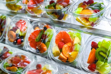 Plastic boxes with pre-packaged fruit salads, put up for sale in a commercial refrigerator