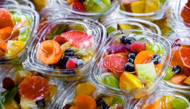 Plastic boxes with pre-packaged fruit salads, put up for sale in a commercial refrigerator