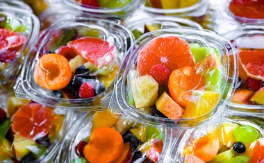 Plastic boxes with pre-packaged fruit salads, put up for sale in a commercial refrigerator