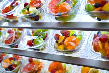 Plastic boxes with pre-packaged fruit salads, put up for sale in a commercial refrigerator