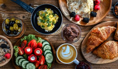 Kahvaltının yanında kahve, portakal suyu, kruvasan, mısır gevreği, çırpılmış yumurta ve krep var..