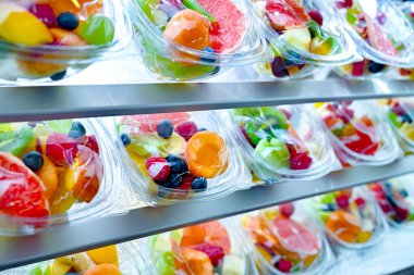 Plastic boxes with pre-packaged fruit salads, put up for sale in a commercial refrigerator