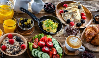 Kahvaltının yanında kahve, portakal suyu, kruvasan, mısır gevreği, çırpılmış yumurta ve krep var..