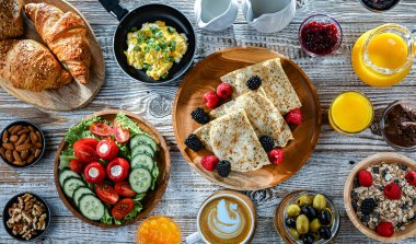 Kahvaltının yanında kahve, portakal suyu, kruvasan, mısır gevreği, çırpılmış yumurta ve krep var..