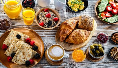 Kahvaltının yanında kahve, portakal suyu, kruvasan, mısır gevreği, çırpılmış yumurta ve krep var..